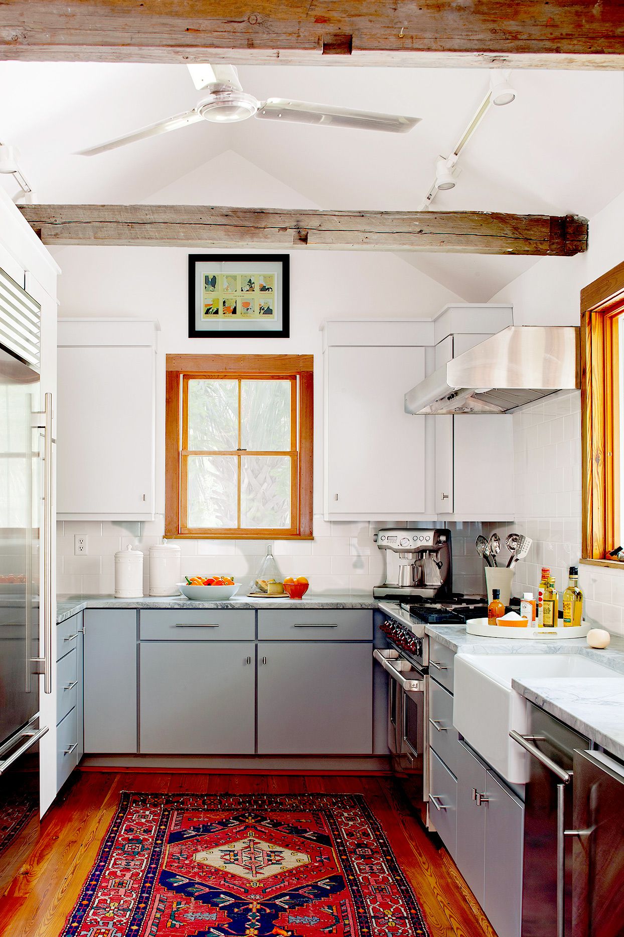 Кухня в стилі кантрі: сіро-блакитні фасади, мармурова стільниця та традиційний килим на дерев'яній підлозі