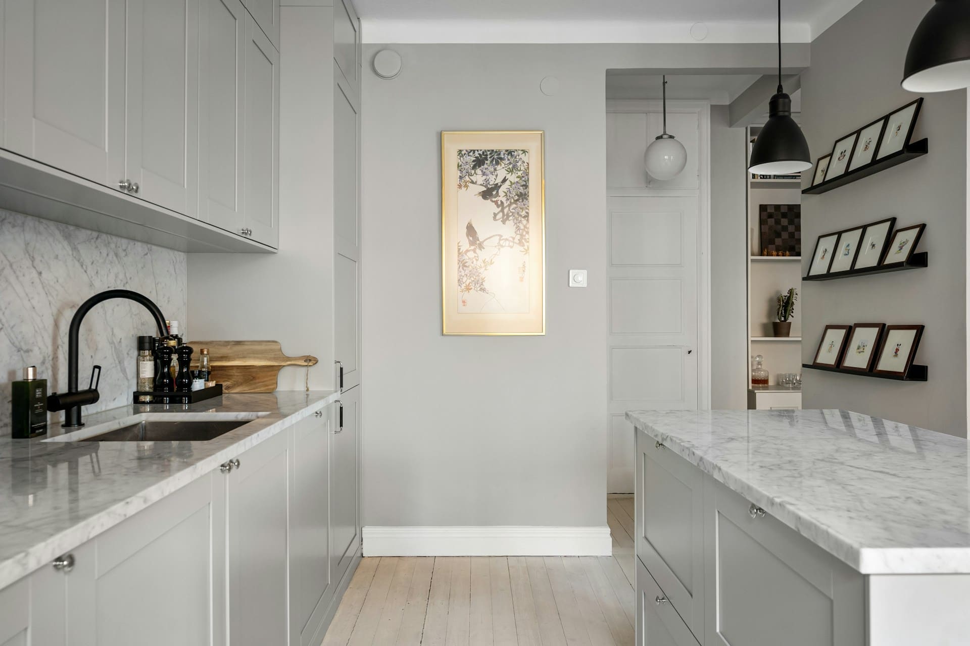 Світло-сіра кухня з мармуровими стільницями та чорними акцентами: змішувач, фурнітура та декор