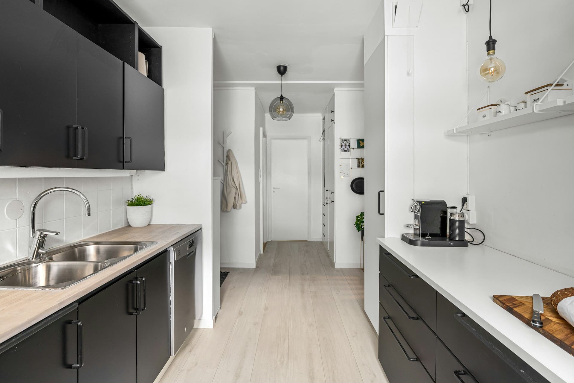 Чорно-біла кухня з білою стільницею та робочою зоною з HPL під світле дерево біля мийки