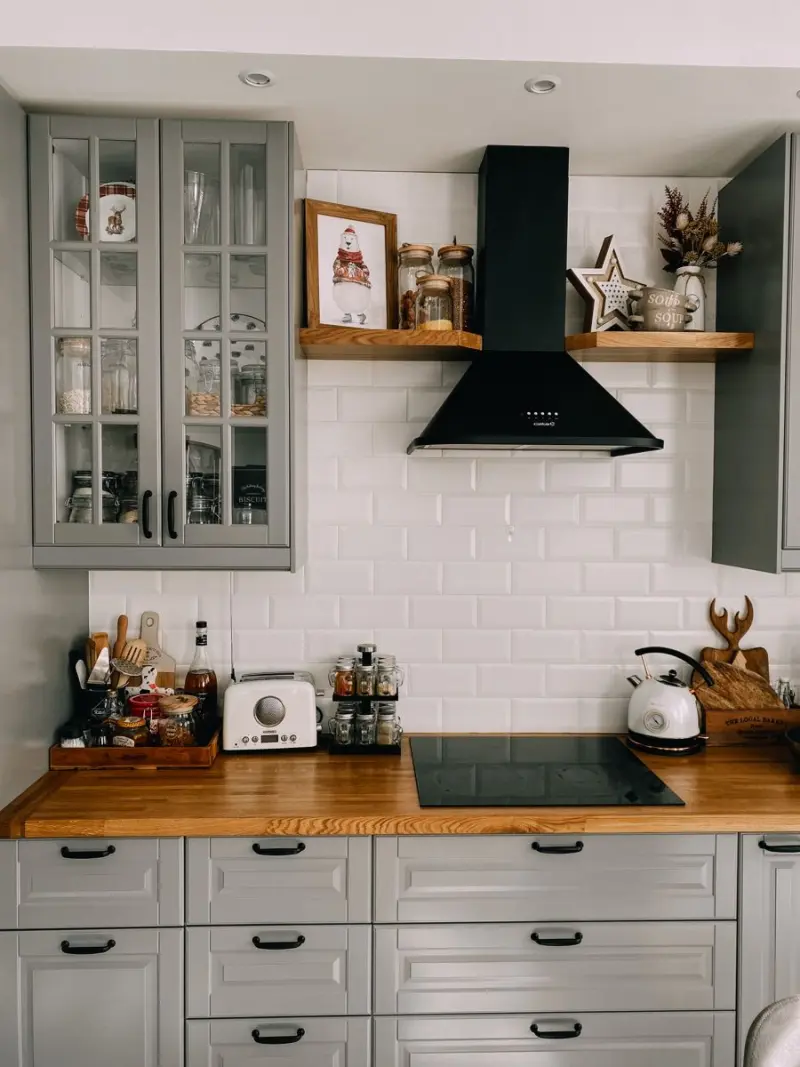 Компактна кухня з сірими фасадами, відкритими полицями, білою плиткою та чорною технікою в ретро-стилі