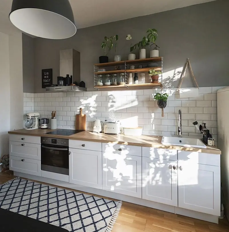 Світло-сіра кухня в стилі неокласика з дерев'яною стільницею, відкритими полицями та рамковими фасадами