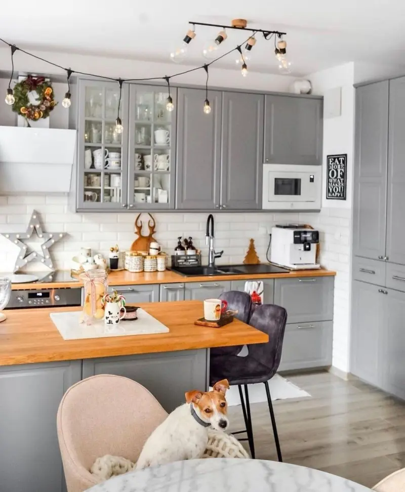 Затишна сіра кухня з традиційними рамковими фасадами та з масивним дерев'яним островом у центрі