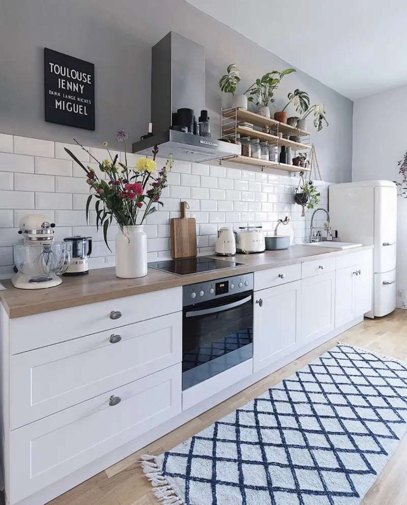 Світла лінійна кухня з білими нижніми модулями, сірими стінами та килимом із чорно-білим геометричним візерунком
