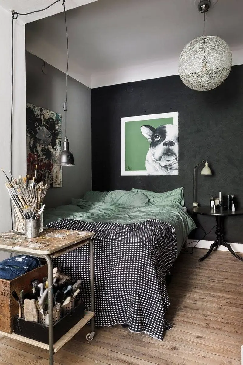 Спальня в індустріальному стилі з чорною акцентною стіною, картиною із зображенням бульдога та візком для приладдя художника