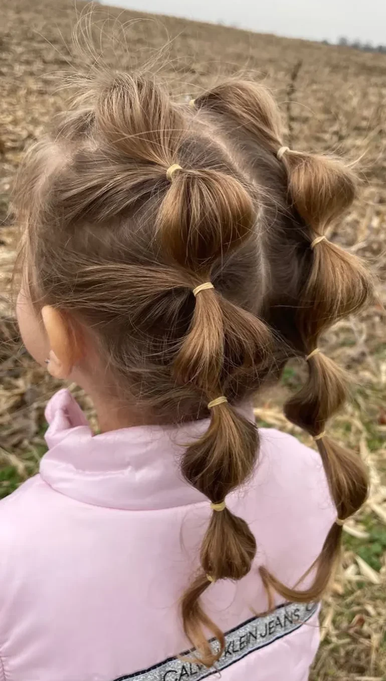 Дві "бульбашкові" коси на довге волосся, де кожна секція зафіксована яскраво-жовтими резинками для створення об’єму.